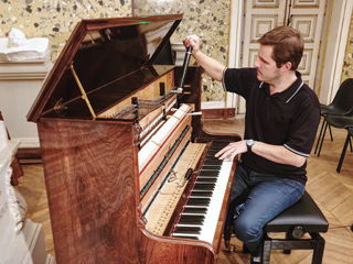 Photo de Julien Bret préparant un piano droit Roller et Blanchet pour un concert